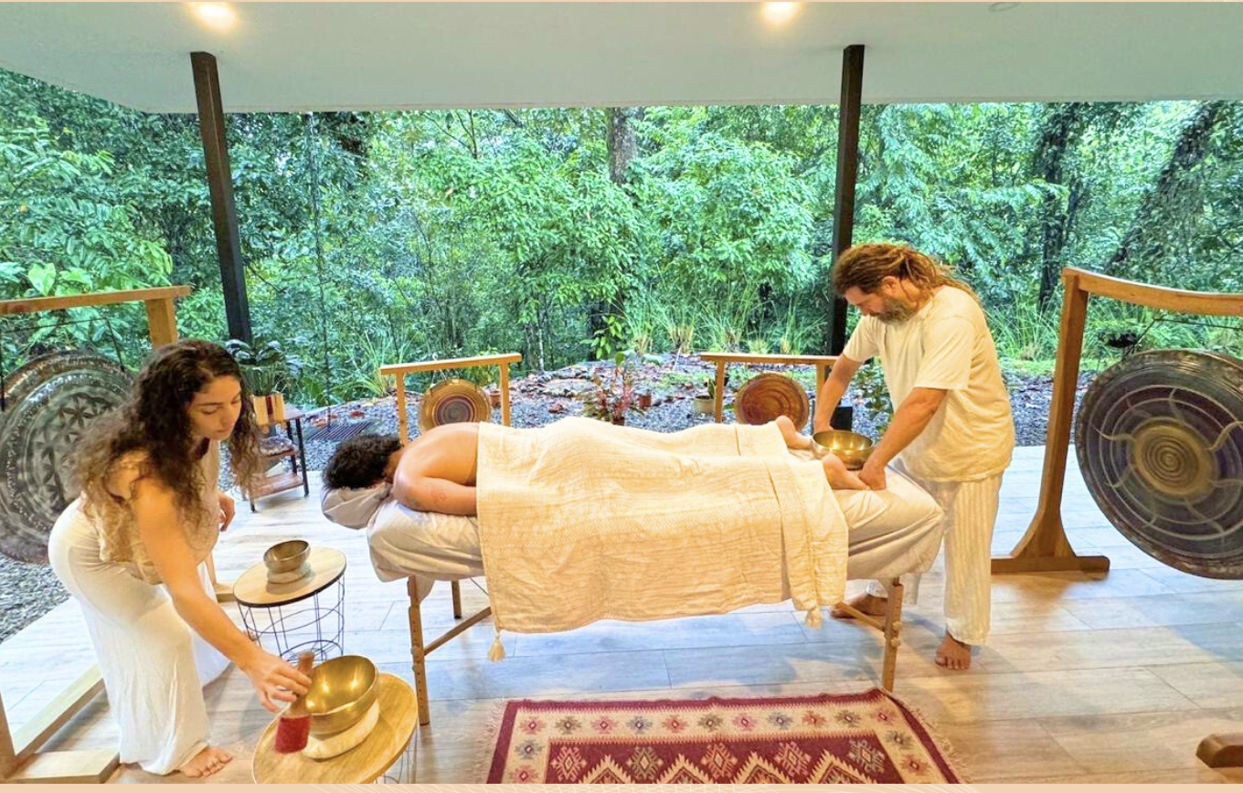 Lotus giving a massage while Yoselyn plays singing bowls beside the guest