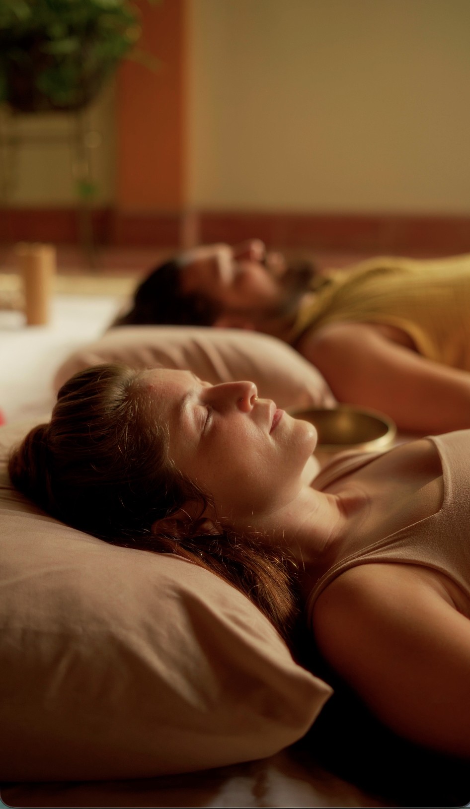 A couple resting side by side with a singing bowl during a sound experience